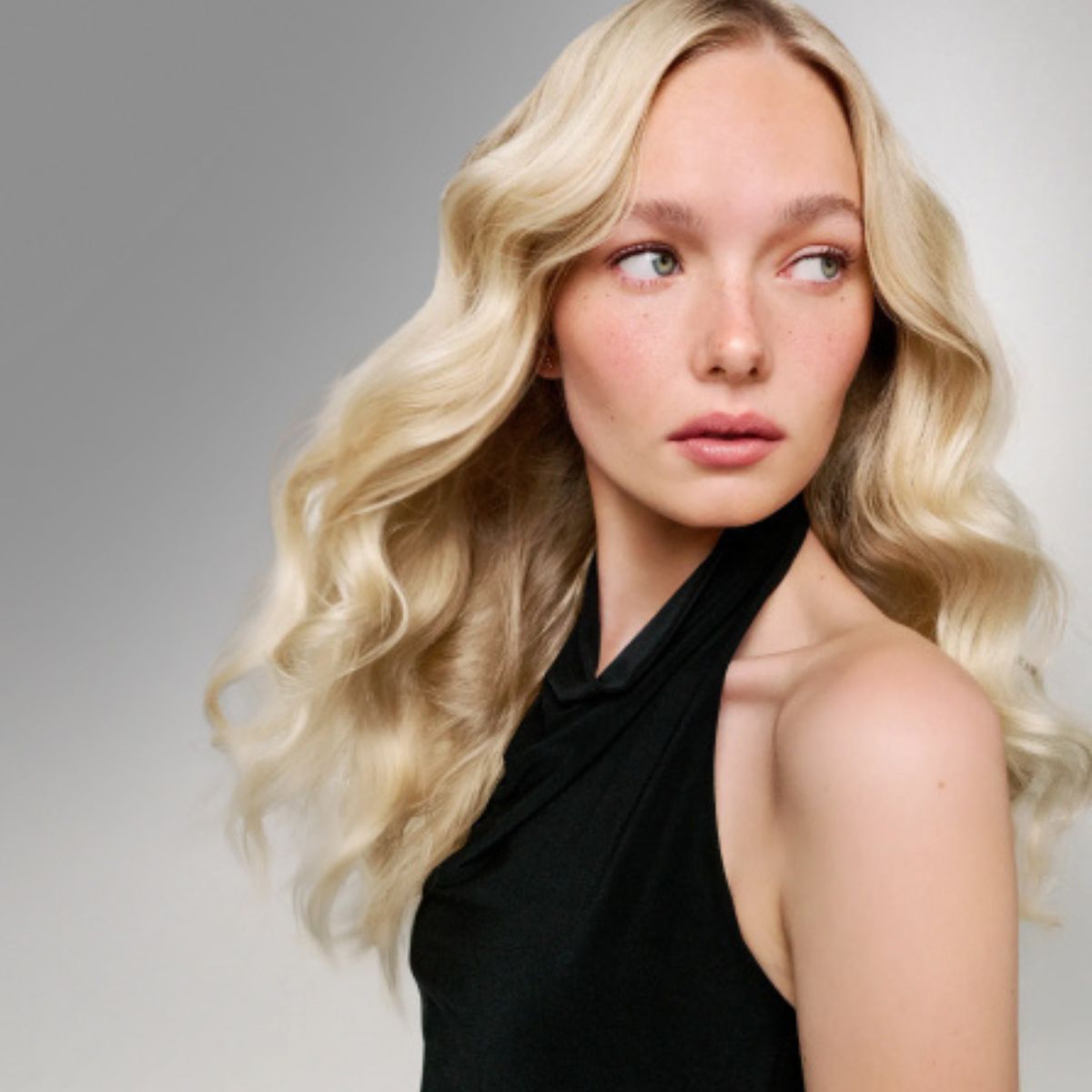 Mannequin aux cheveux blonds sur fond gris après l'utilisation des produits hydratants Blacklight Blonde Science